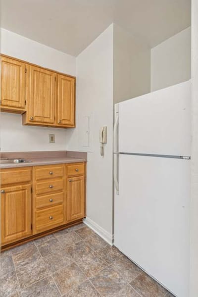 Kitchen area with wooden cabinets and refrigerator.