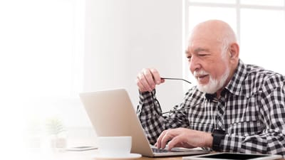 Senior man using a laptop in a bright room