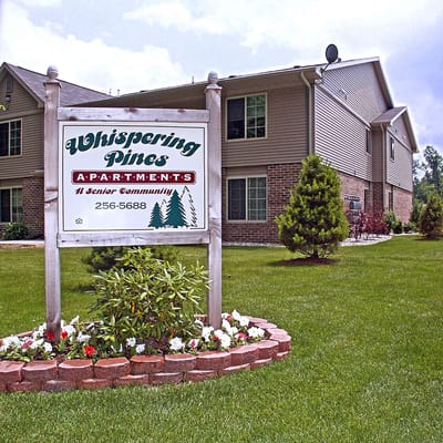 Sign for Whispering Pines Apartments in front of the building