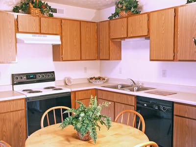 A kitchen area with wooden cabinets and a table