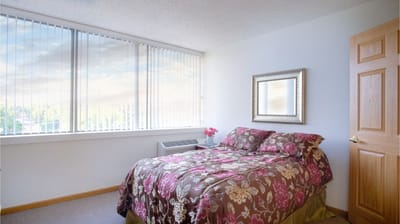 Cozy bedroom interior with floral bedding and large windows