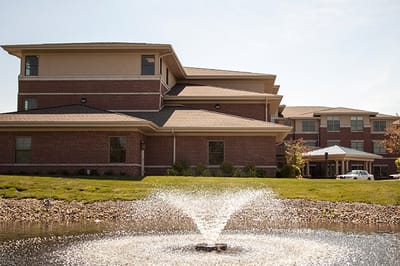 Exterior view of a senior living facility with a fountain