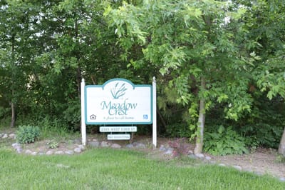 Signage for Meadow Crest Senior Apartments amidst greenery