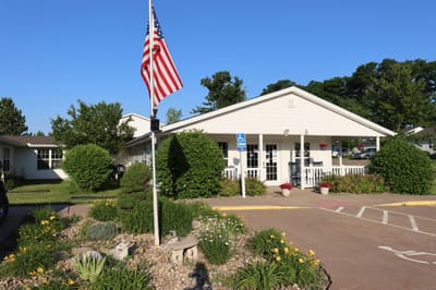 Exterior view of Meadowcrest Senior Apartments with garden and flag