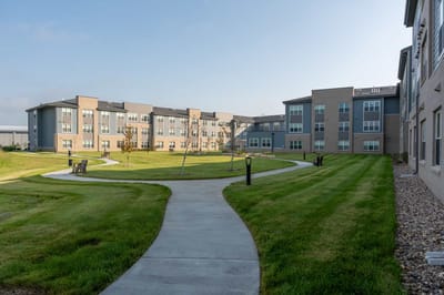 Pathway leading through green outdoor space with buildings