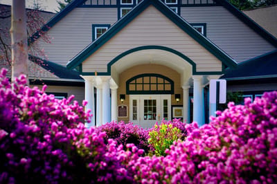 Entrance of a senior living facility surrounded by flowers