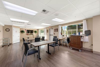 A bright room with tables and chairs in a facility