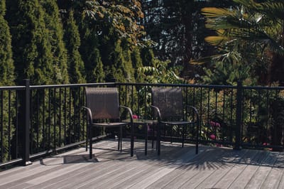 Outdoor seating area with two chairs surrounded by greenery