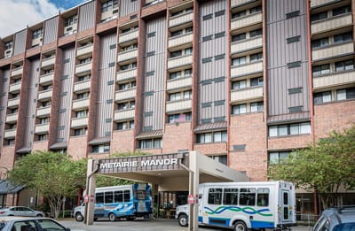 Exterior view of Metairie Manor with transport vehicles