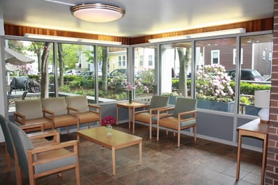 Bright common area with seating and views of gardens