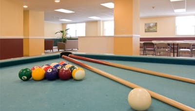 Billiard table with cue sticks in a common area