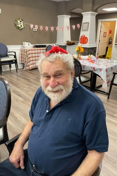 A smiling resident with a playful hat in a decorated common area