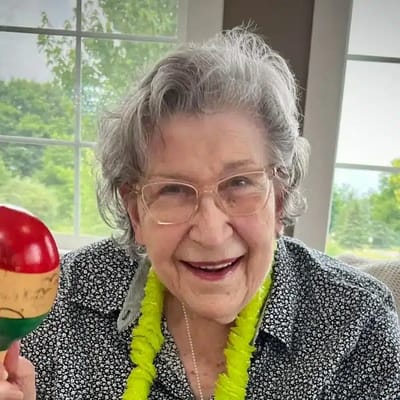 Resident enjoying a festive activity with a maraca