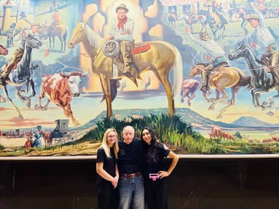 Residents and staff smiling in front of a mural