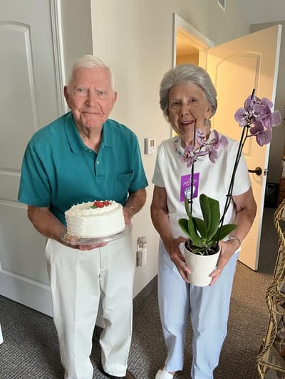 A senior couple celebrating with a cake and orchid