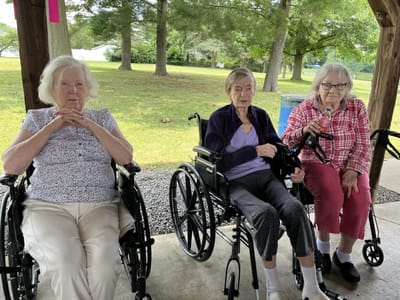 Three residents enjoying time outside in wheelchairs