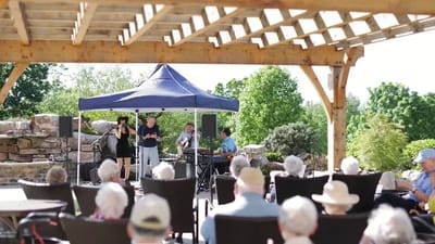 Residents enjoying live music under a shaded gazebo