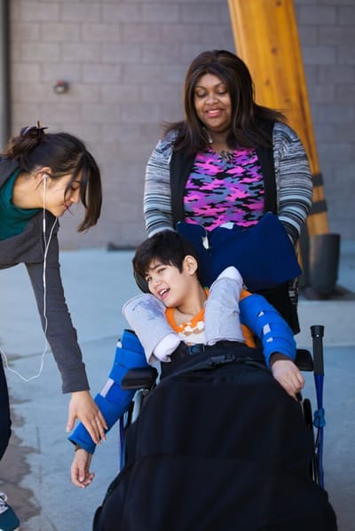 Caregiver assisting a child in a wheelchair.