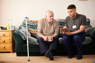 Caregiver assisting a senior man in a cozy living room