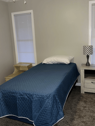 A simple, furnished resident bedroom with blue bedding