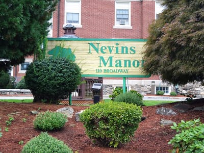 Outdoor sign of Nevins Manor surrounded by greenery