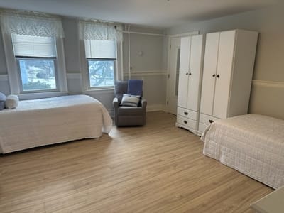 A private resident room with two beds and a chair