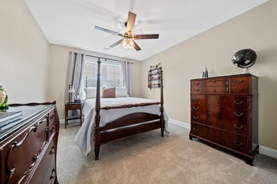 A well-furnished private resident room with a bed and dresser