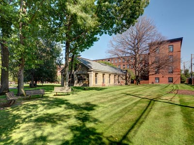Exterior view of Robinson Cuticura Mill Apartments with lawn and trees