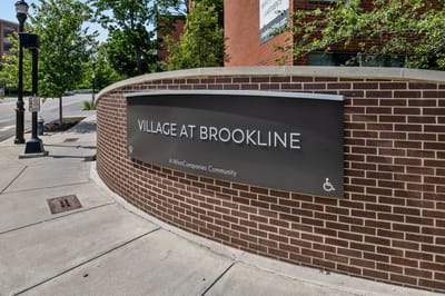 Sign for Village At Brookline on a brick wall
