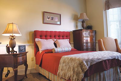 Cozy private resident room with a red bedspread and warm lighting