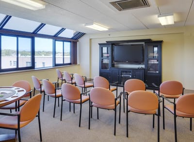 Bright common area with orange chairs and a television