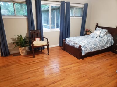 Brightly lit resident room with bed and chair