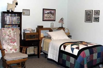 Cozy resident room with quilted bed and chair