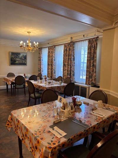 Dining room set up for a meal with floral tablecloths