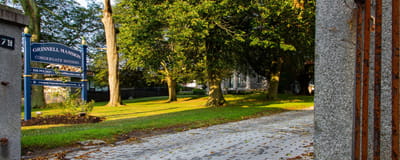 Path leading to Grinnell Mansion with trees and signage