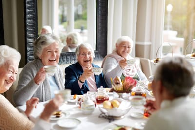 Residents enjoying tea and laughter at a dining table