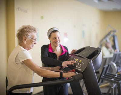 Senior resident exercising with staff support