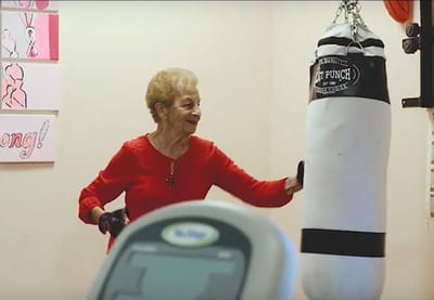 Senior resident engaging with a punching bag in an activity room.