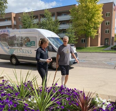 Staff member assisting a resident outdoors near the facility van