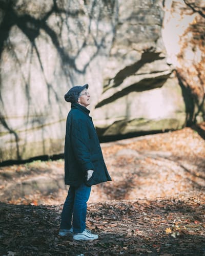 An elderly woman enjoying nature in a park setting