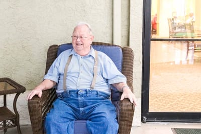 Smiling senior man sitting outside in a comfortable chair