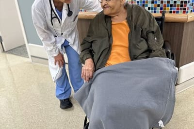 Medical staff interacting with a resident in a facility corridor
