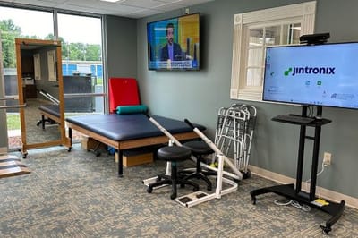 Physical therapy area with exercise equipment and a TV