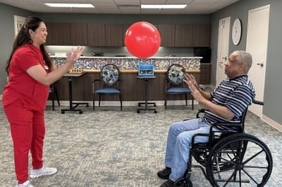 Staff member and resident playing with a red balloon indoors