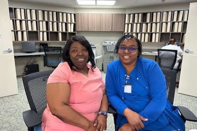 Two staff members smiling in an indoor setting