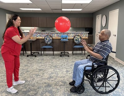 Staff member and resident playing catch with a balloon