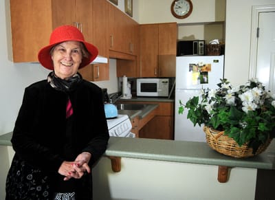 Senior resident smiling in a cozy kitchen.