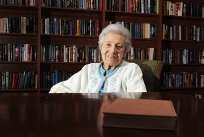 An elderly woman smiling in a library setting
