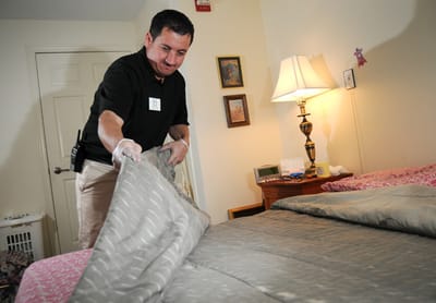 Staff member making a resident's bed in a private room