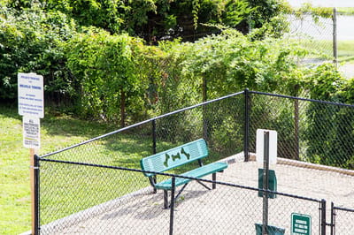 Outdoor dog park area with a bench and signage